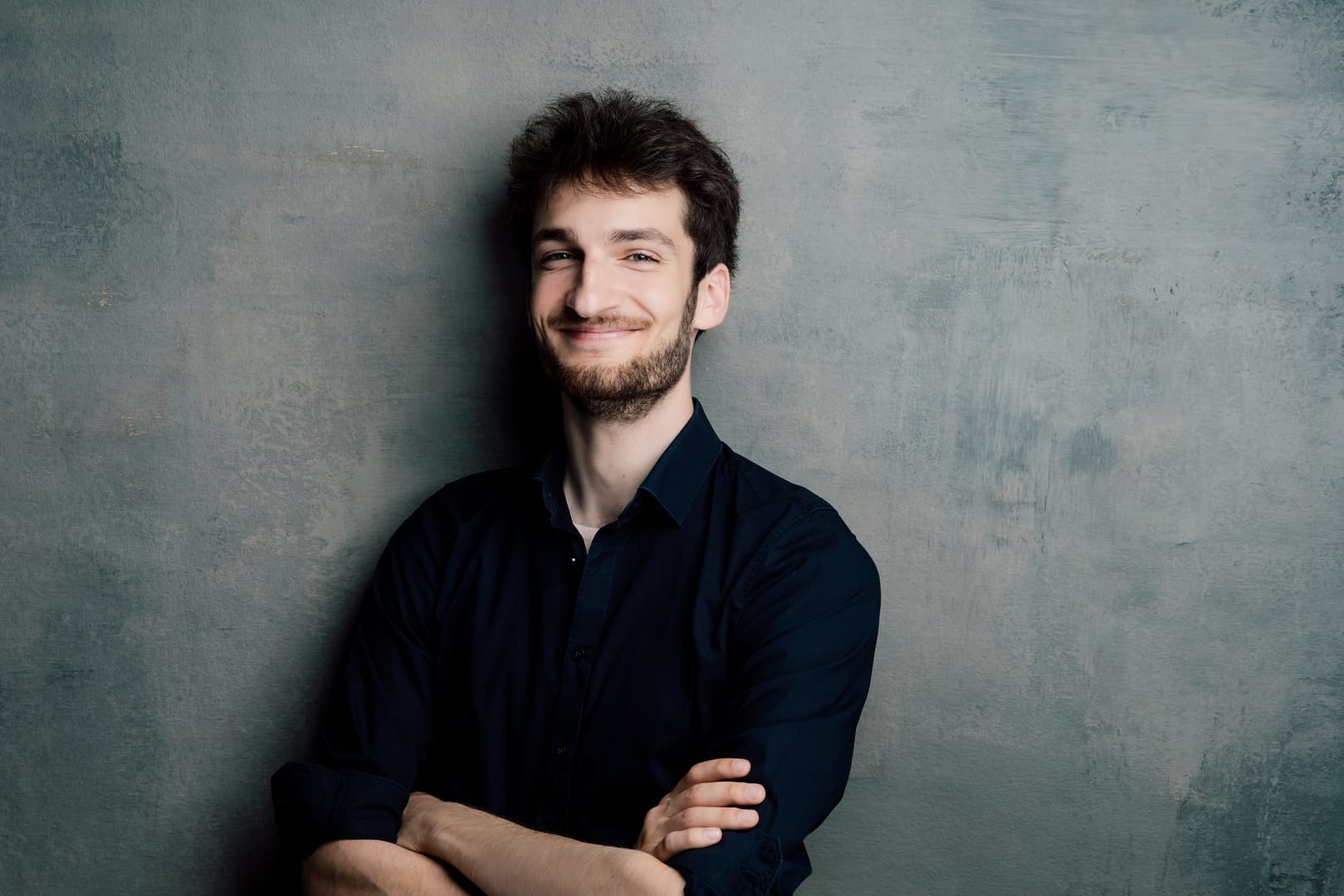 Sandro Balk mit verschränkten Armen vor einer grauen Wand.
